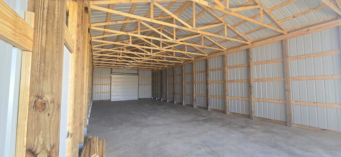 Interior of post frame building showing wood trusses