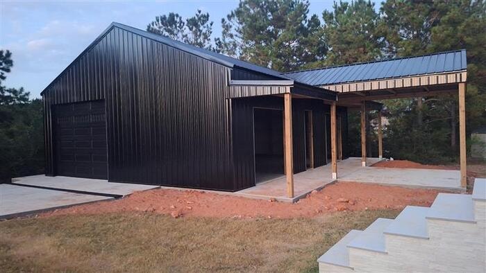 Black post frame building with covered porch